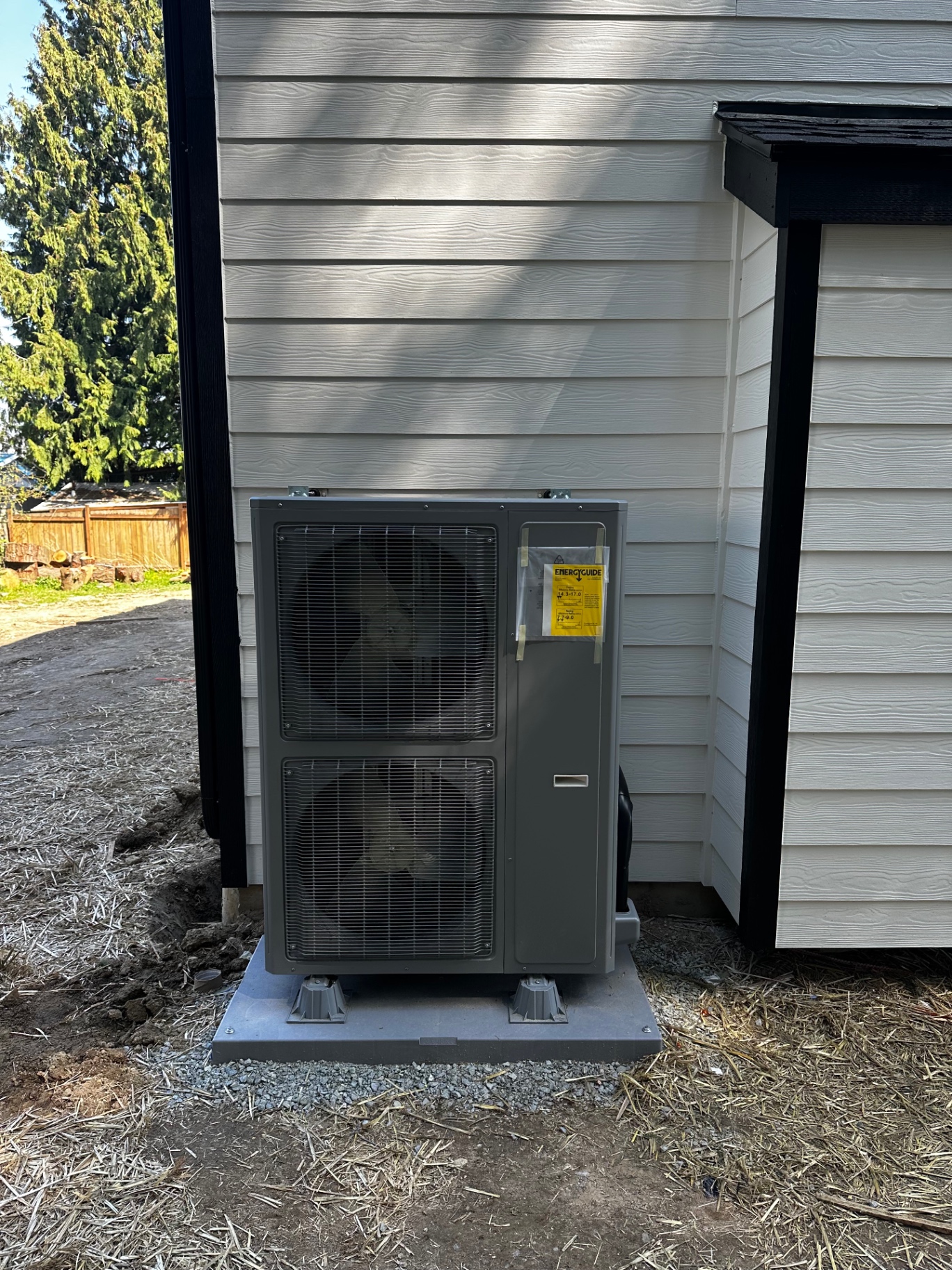 Dual-fan heat pump outdoor unit installed beside a home